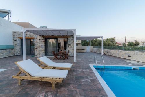een patio met 2 ligstoelen en een zwembad bij EL.MA.RA. Luxury Villas in Kókkinos Pírgos