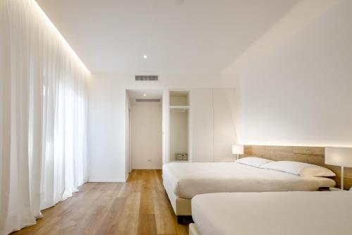 two beds in a room with white walls and wooden floors at Hotel Onda Marina in San Teodoro