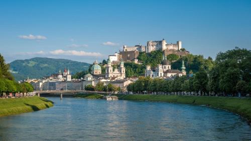 a river in front of a city with a castle at LUXURY STAY SALZBURG City in Salzburg