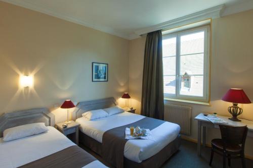 pokój hotelowy z 2 łóżkami i oknem w obiekcie Le Corbeau w mieście Auxonne