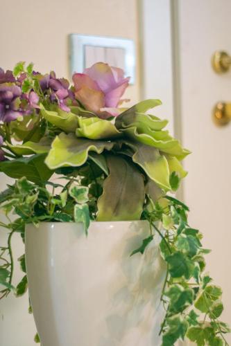 a white vase with flowers in it at Juliet House in Verona