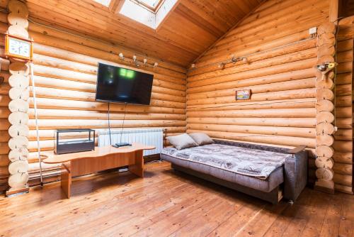 a bedroom with a bed and a tv in a log cabin at Domik na Berezovoy 6 in Pushkin