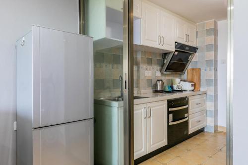 a kitchen with white cabinets and a refrigerator at Lavendar Duplex Apartment in Guangzhou