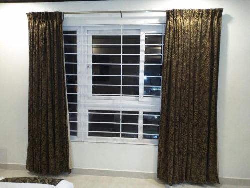 a window with brown curtains in a room at saravanaa residency in Madurai