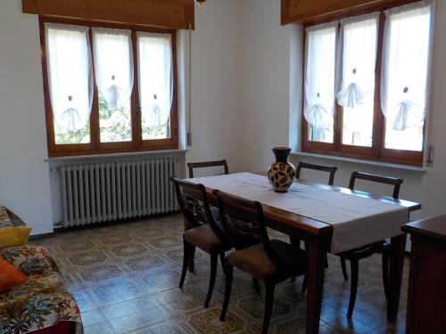 a dining room with a table and chairs and windows at Casa Romme in Tornolo