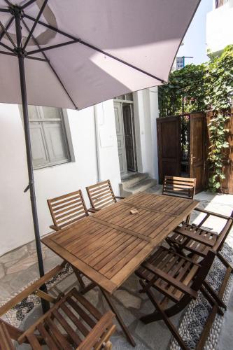 a wooden table and chairs with an umbrella at Nisyros Views in Mandrakion