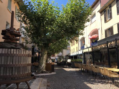 a tree in the middle of a street with tables and chairs at Bastide du Levant - 50m plage - Rez de jardin in Sainte-Maxime
