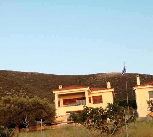 a house with a flag in front of a hill at Lazy Farm in Prásinon