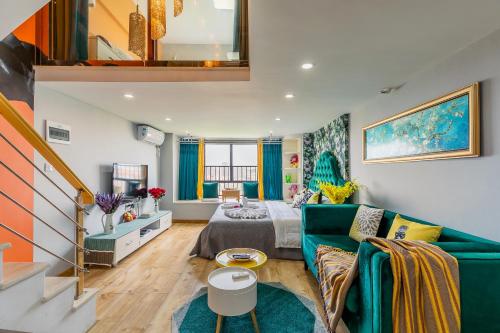 a living room with a green couch and a bed at Lavendar Duplex Apartment in Guangzhou