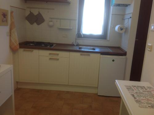 d'une cuisine avec des placards blancs, un évier et une fenêtre. dans l'établissement Appartamento Manuela, à Civitanova Marche