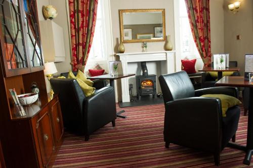 a living room with two chairs and a fireplace at Eskdale Hotel in Langholm