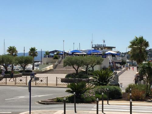 a park with benches and blue umbrellas on a street at Bastide du Levant - 50m plage - Rez de jardin in Sainte-Maxime