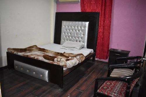 a bedroom with a bed and a chair at Sitara Hotel in Islamabad