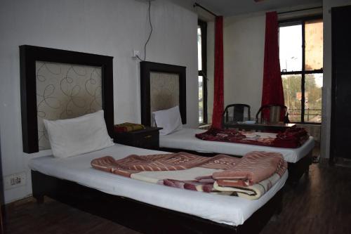 two beds in a room with two windows at Sitara Hotel in Islamabad