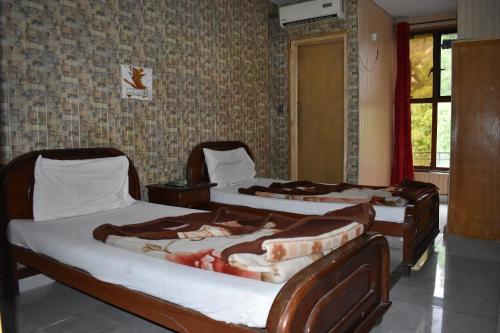 a room with three beds in a room at Sitara Hotel in Islamabad