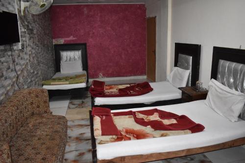 a room with three beds and a couch at Sitara Hotel in Islamabad