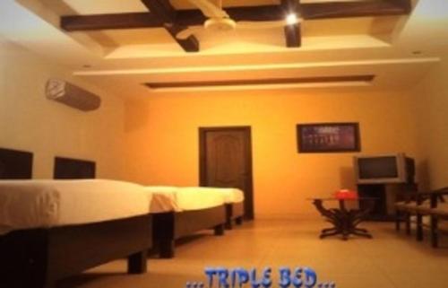 a bedroom with two beds and a television in it at Hotel Johar View in Lahore