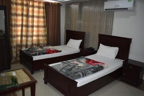 two beds in a hotel room with a table at Hotel Kashmir Inn in Rawalpindi