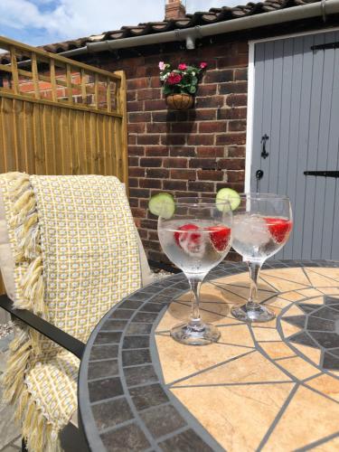 two wine glasses sitting on a table on a patio at Archie's Cottage in Lincoln