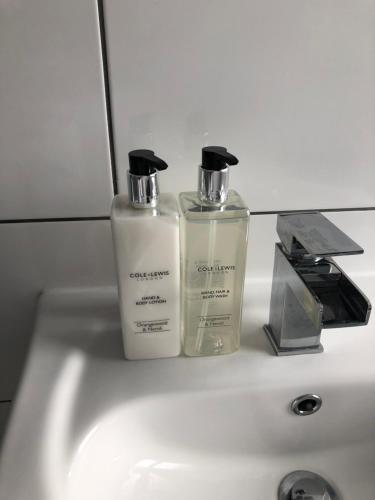 two bottles ofodorizers sitting on a bathroom sink at Archie's Cottage in Lincoln