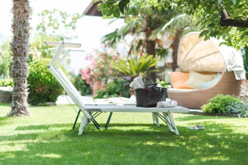 a white chair and a table in the grass at Hotel - Appartements Schmied Hans in Schenna