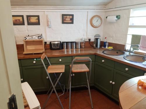 a kitchen with green cabinets and a counter with two stools at KEYFIELD TERRACE SERVICED APARTMENTS in Saint Albans