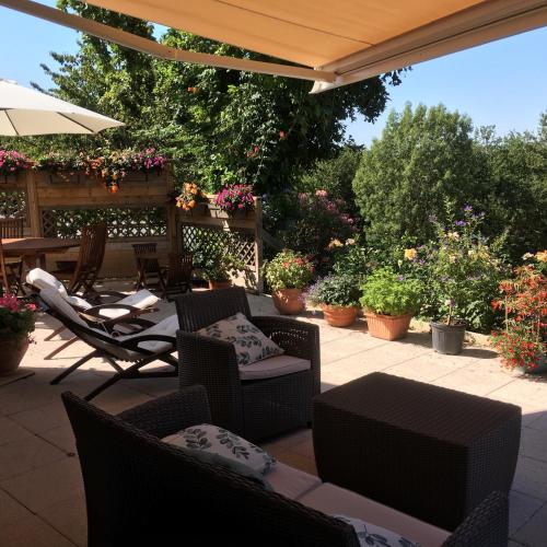 a patio with chairs and an umbrella and plants at Le Relais des Malettes Chambres d'hôtes B&B in Francheville