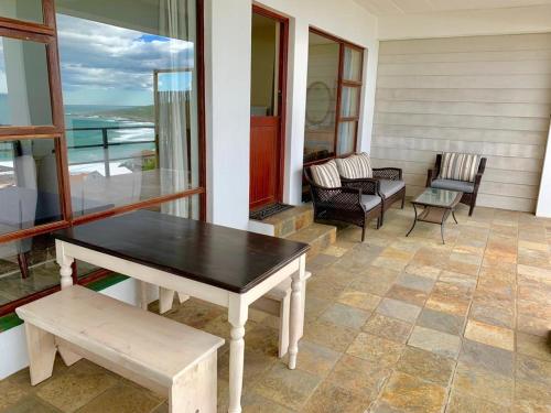 a porch with a table and chairs on a house at Captain Sunshine Guest House in Jongensfontein