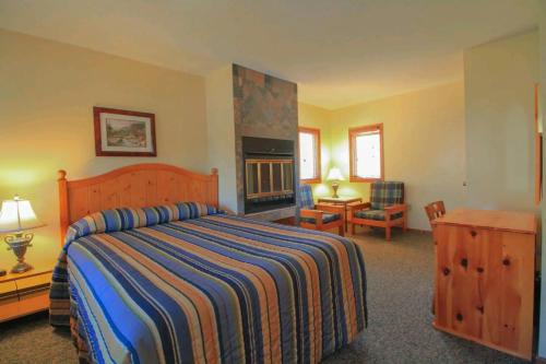 1 dormitorio con 1 cama grande y chimenea en Sunny Point Resort Ltd. en Otter Lake