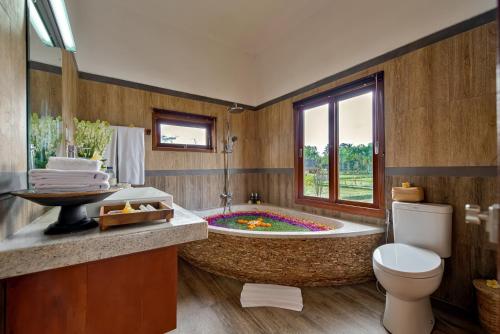 a bathroom with a large tub with a toilet and a sink at Cenik Villa Ubud in Ubud