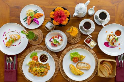 a wooden table with plates of food and cups of coffee at Cenik Villa Ubud in Ubud