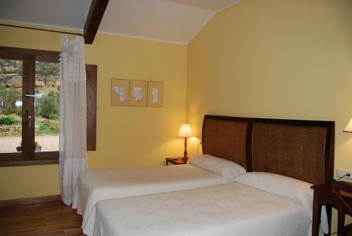 two beds in a room with yellow walls and a window at Hotel Del Verde Al Amarillo in Peñasrubias de Pirón