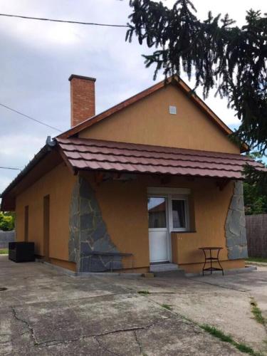 una pequeña casa amarilla con una mesa delante en Jázmin Apartmanok, en Mórahalom