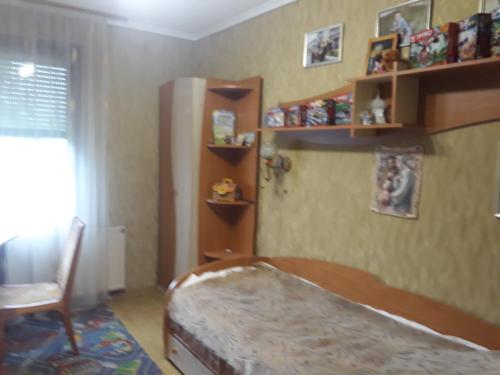 1 dormitorio con cama, silla y estanterías en Затишок, en Volovets