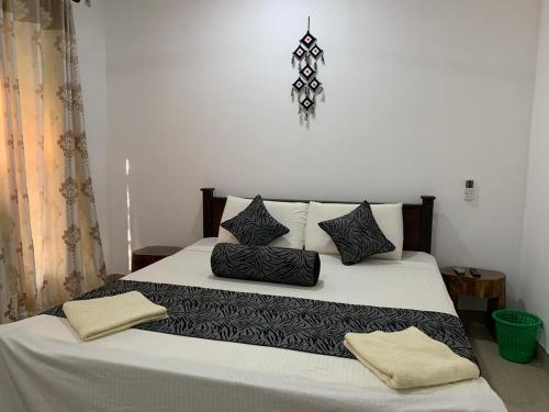 a bedroom with a large bed with black and white pillows at Shan Home Stay Sigiriya in Sigiriya