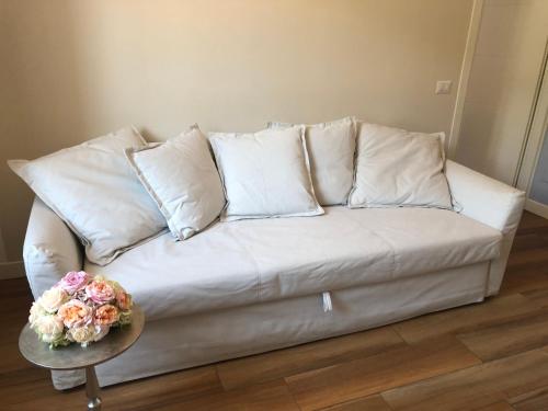 a white couch with pillows and a table with flowers at Vivi Cernobbio, la sua arte, la sua magia in Cernobbio
