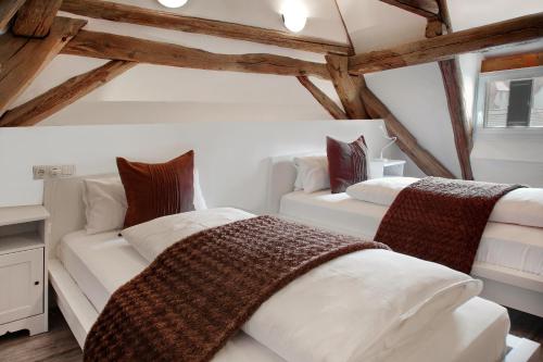 2 Betten in einem Dachzimmer mit Holzbalken in der Unterkunft Gästehaus Edelzimmer in Rothenburg ob der Tauber
