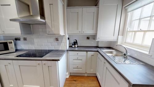 
a kitchen with white cabinets and white appliances at Bishop's Gate Hotel in Derry Londonderry
