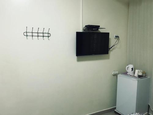 a bathroom with a white wall with a television on the wall at Ashel Hotel in Beer Sheva