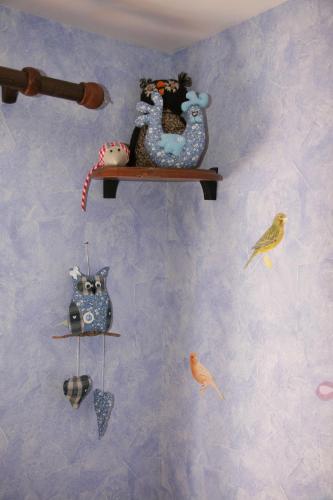 a wall with a shelf with toys and birds on it at Gîte Schlitteur Et Sapiniere in Breitenbach