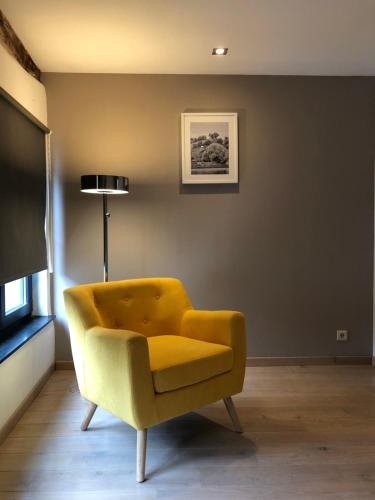 a yellow chair in a living room with a television at Mademoiselle Citadelle in Namur
