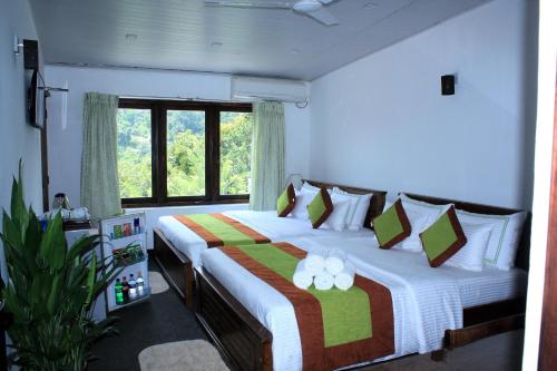 a bedroom with two beds and a large window at Imaaga Kandy Residence in Kandy