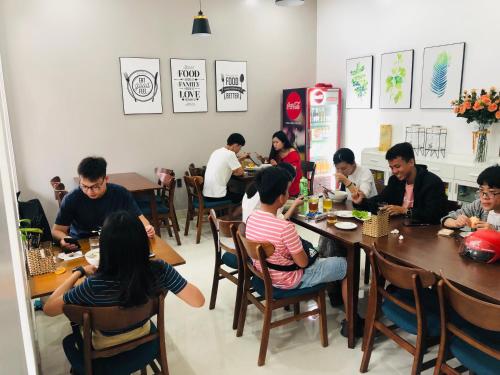 a group of people sitting at tables in a restaurant at Peaceful House Hostel in Dong Hoi