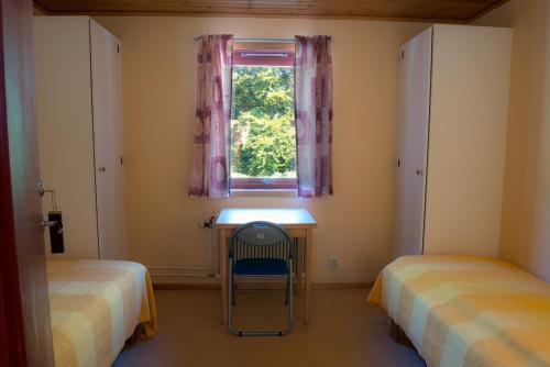 a bedroom with two beds and a desk and a window at Halens Camping och Stugby in Olofström