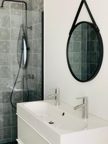 uma casa de banho com um lavatório e um chuveiro com um espelho. em Zitoun em Nieuwpoort