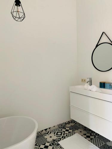 een badkamer met een bad, een wastafel en een spiegel bij Zitoun in Nieuwpoort