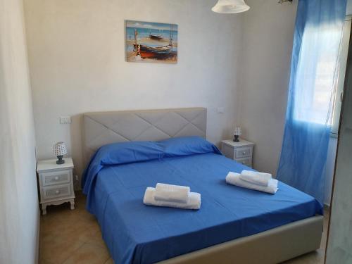 a bedroom with a blue bed with two towels on it at Casa Vacanze a 200 metri dal mare in Triscina