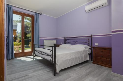 een slaapkamer met paarse muren, een bed en een raam bij Il Castellano Vacanze in Porto SantʼElpidio