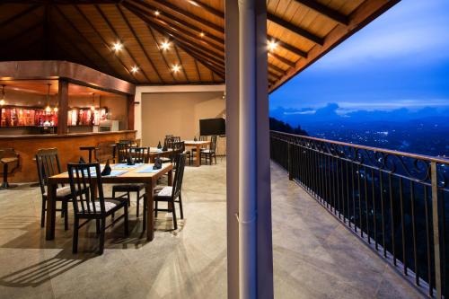 a dining room with a table and chairs on a balcony at Ceyloni Panorama Resort in Kandy