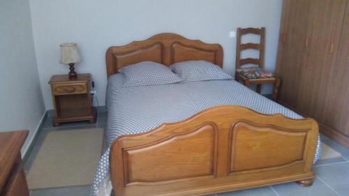 1 dormitorio con cama de madera y silla de madera en Maison de Romagers en Aumont-Aubrac
